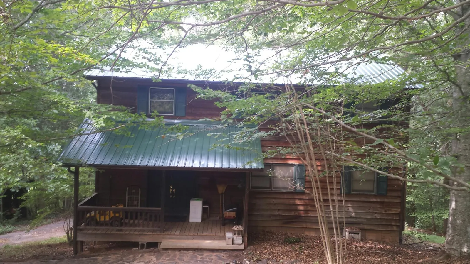Green metal roof and covered porch on a log cabin in Lafayette